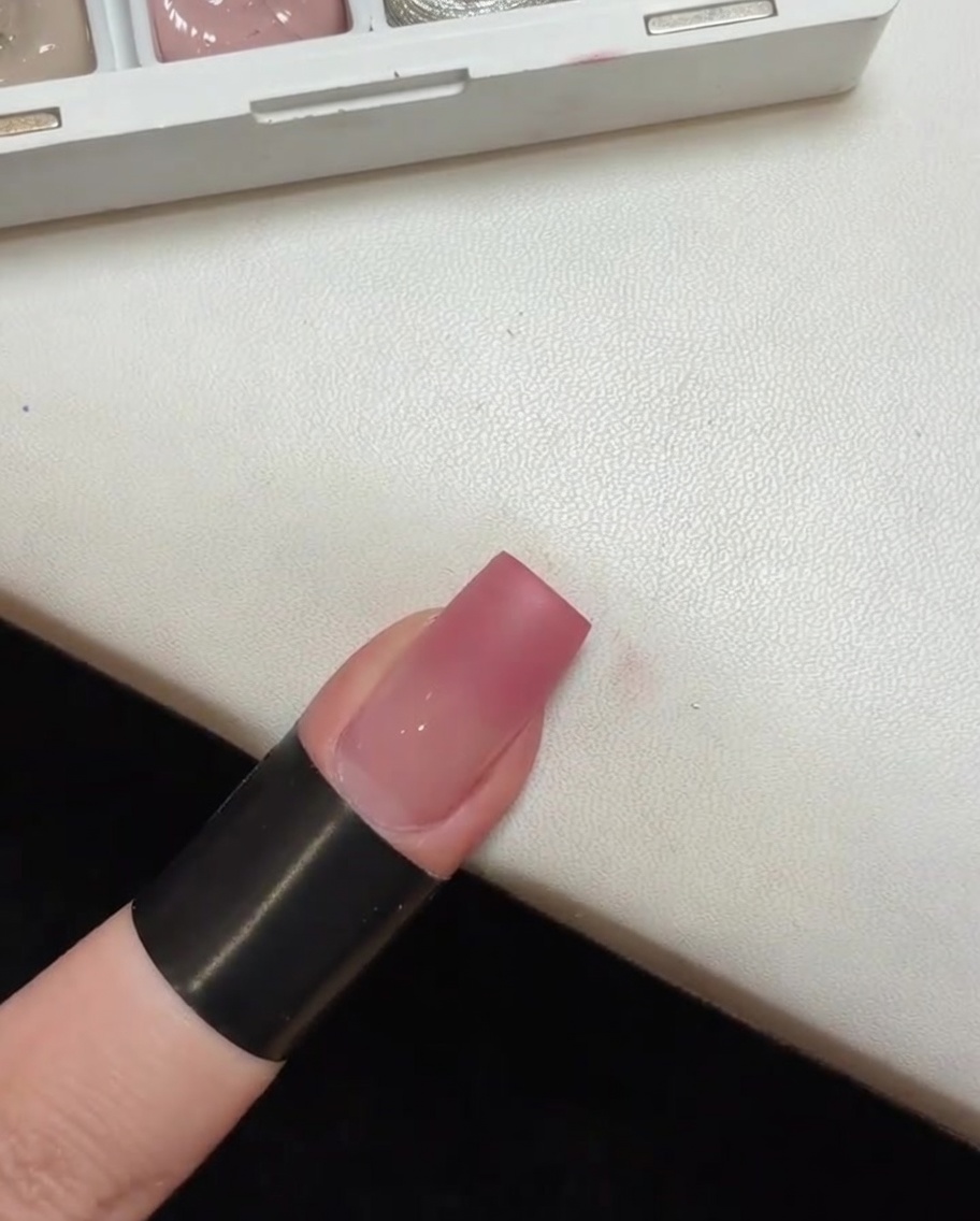 小型ポータブルUVライトの中で硬化されているピンクグラデーションのネイル。