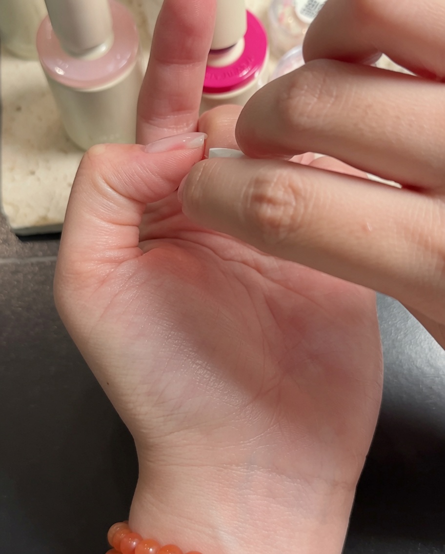 中指と薬指の先端にホワイトジェルを塗り、グラデーションを作っている様子。
