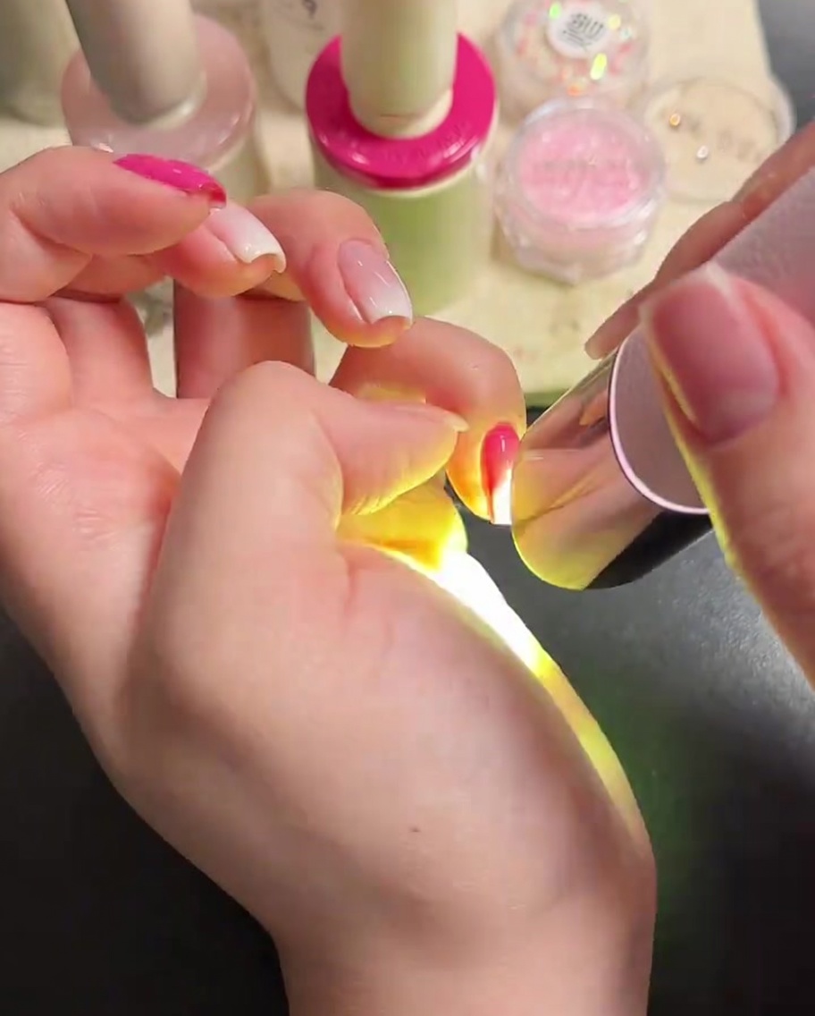 爪にクリアな光沢トップコートを塗布している様子。
