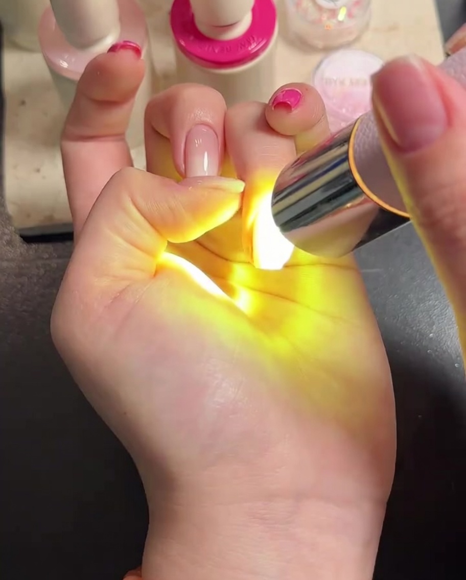 トップコートを塗った指をLEDライトで硬化させている様子。