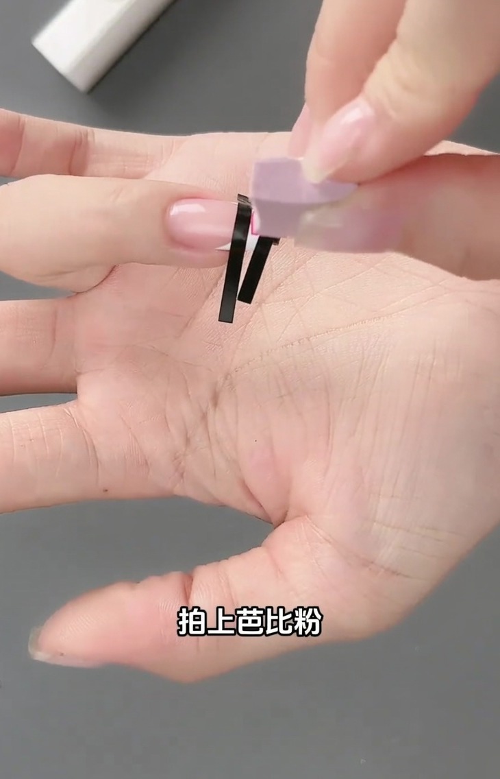 スポンジツールを使って、フレンチステッカーの上からライトピンクのジェルを叩き込んでいる様子。
