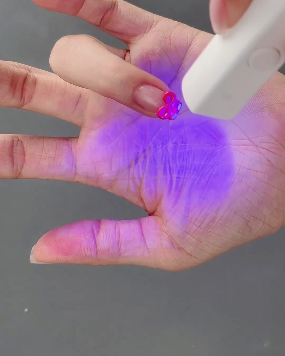 作ったばかりの3Dリボンを硬化させるため、ネイルランプの下に指を置いている様子。