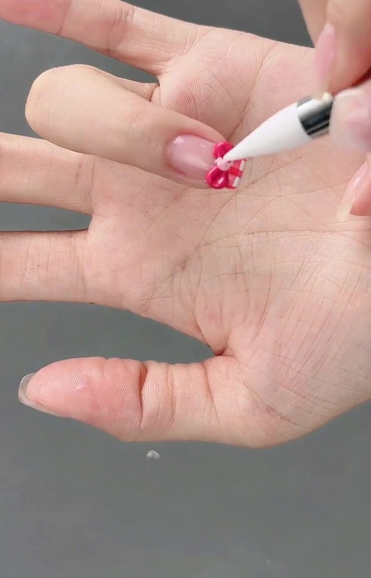 細筆を使って、3Dリボンの中央に小さなライトピンクのジェルを置いている様子。