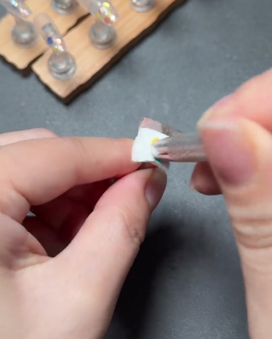 小さな筆でライトピンクのジェルをポンポンと叩き込み、甘皮側からなめらかなグラデーションを作っている様子。
