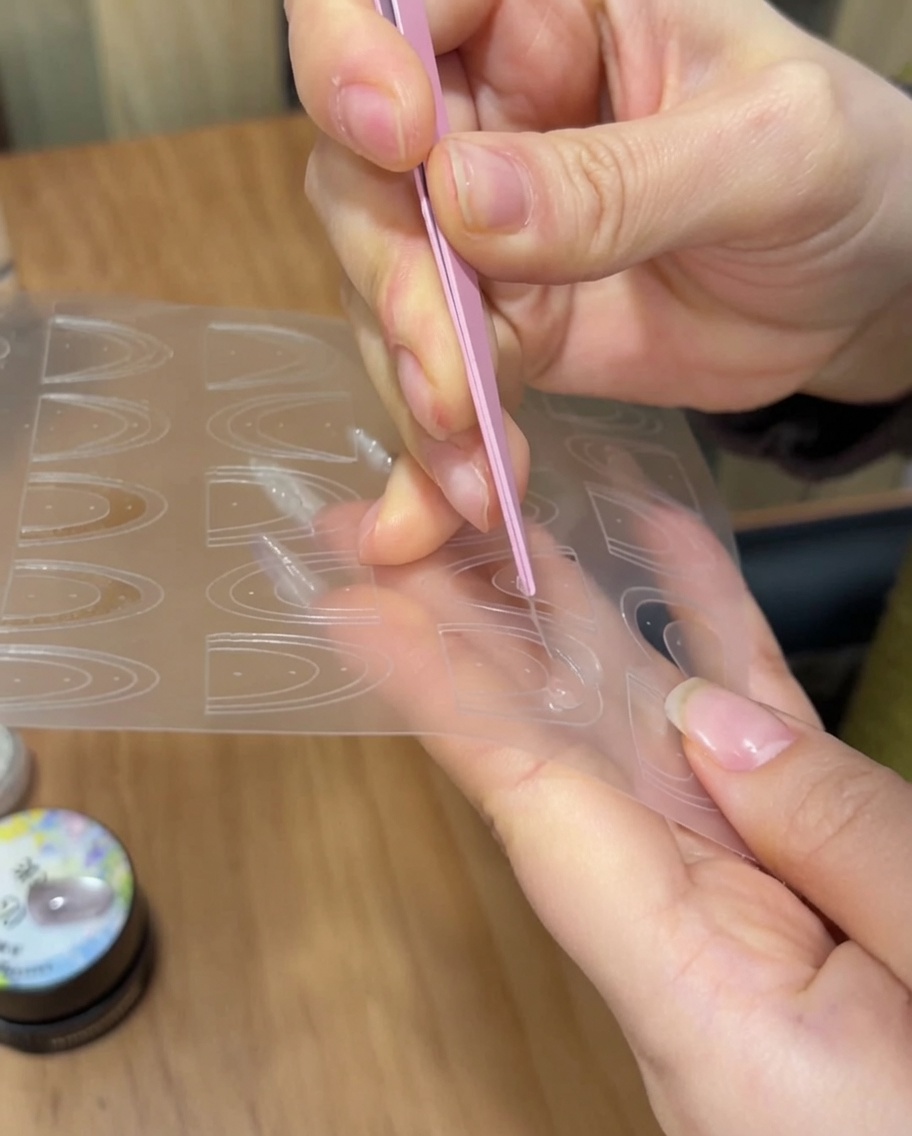 ピンセットを使って、フレンチネイル用のガイドシールを爪先に貼っている様子。