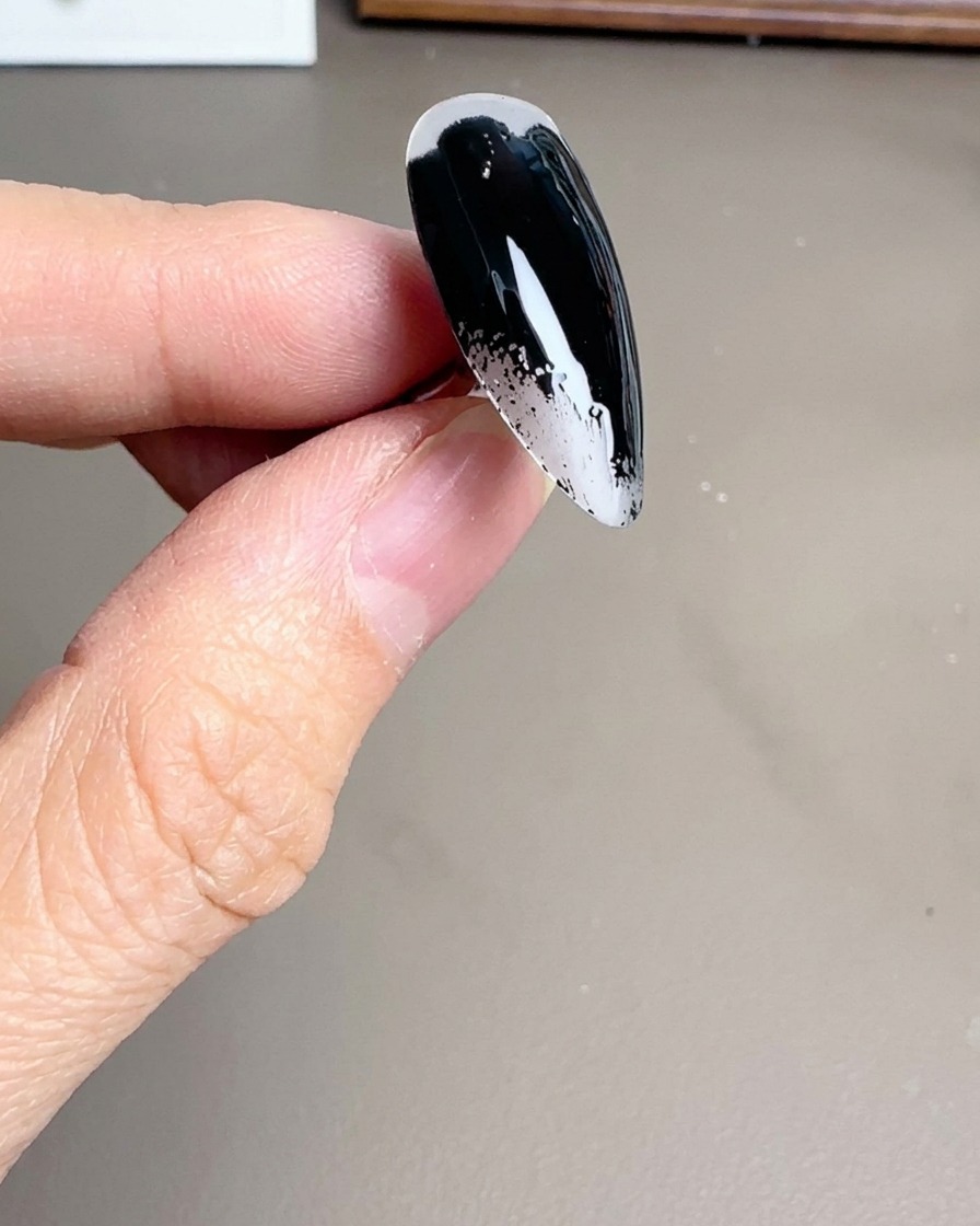 スティレットネイルチップに艶やかな黒のジェルポリッシュを塗っている様子。
