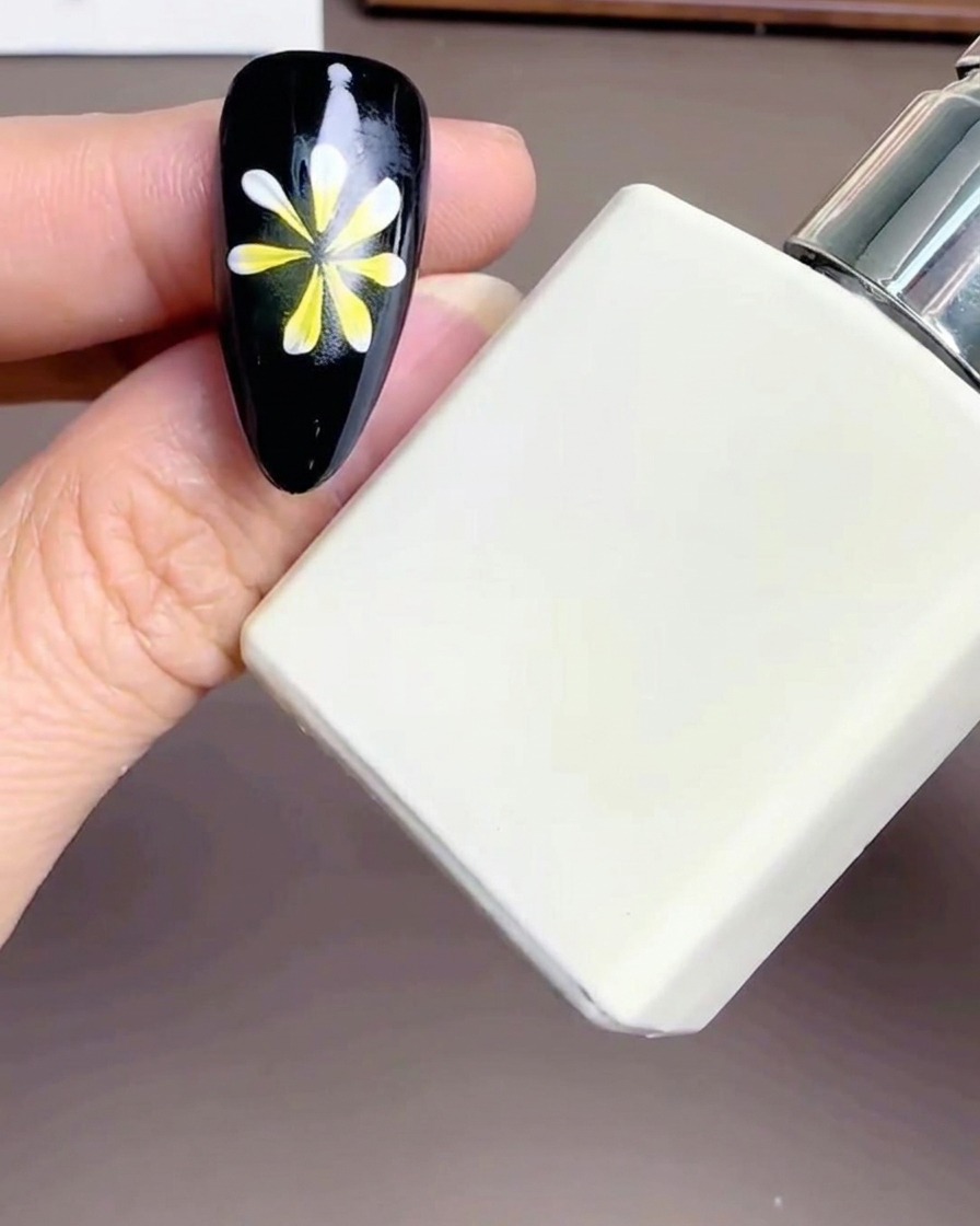 白いトップコートのボトルと、花柄が描かれたネイルチップ。