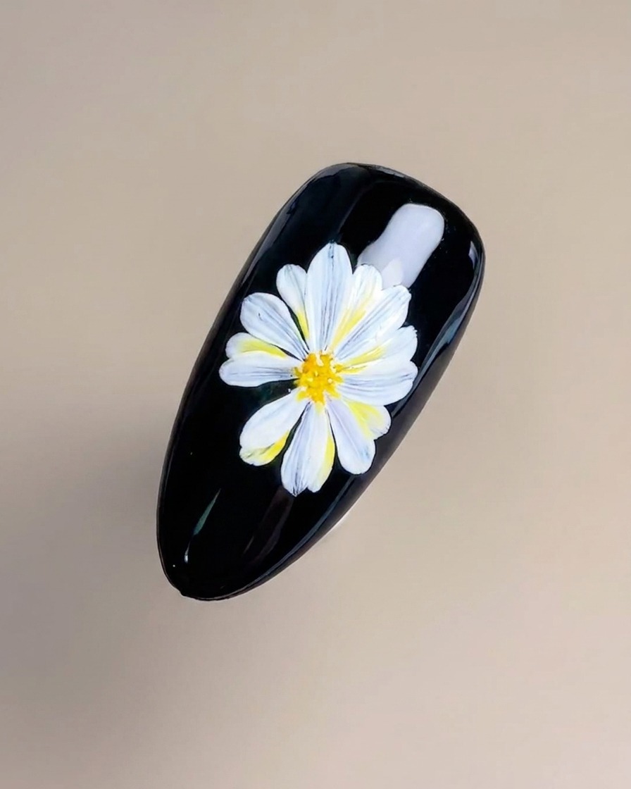 細いライナーブラシで、花芯に黄色とオレンジの繊細な線を描き加えている様子。