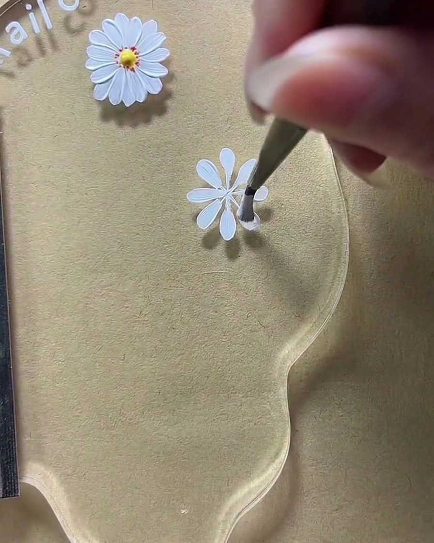 ネイルアートパレット上で、ブラシを使って白い花びらの形状を広げている拡大図。