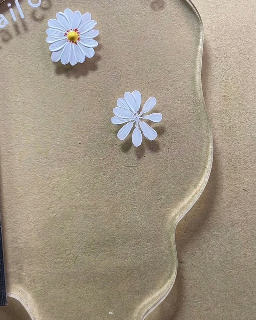 ネイルアートパレット上で、8枚の花びらを持つ白いデイジーのデザインが完成している拡大図。