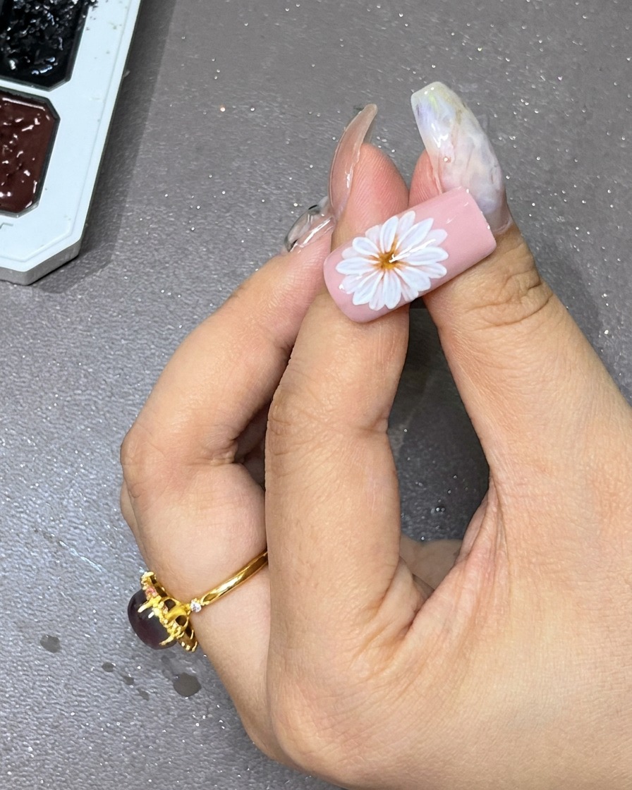白い花の中央に、黒いジェルでドットを打っているクローズアップ写真。