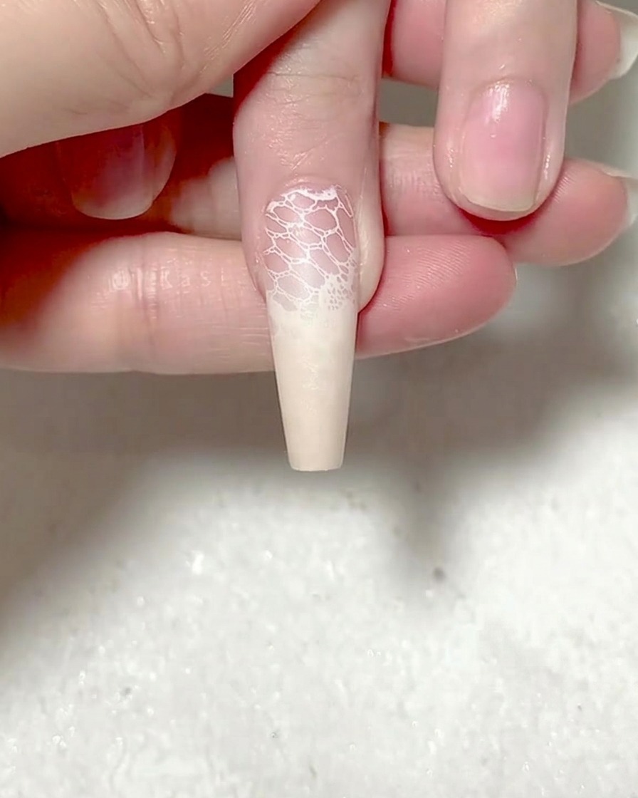 ピンセットで赤いバラのシールを爪の中央に配置している様子。