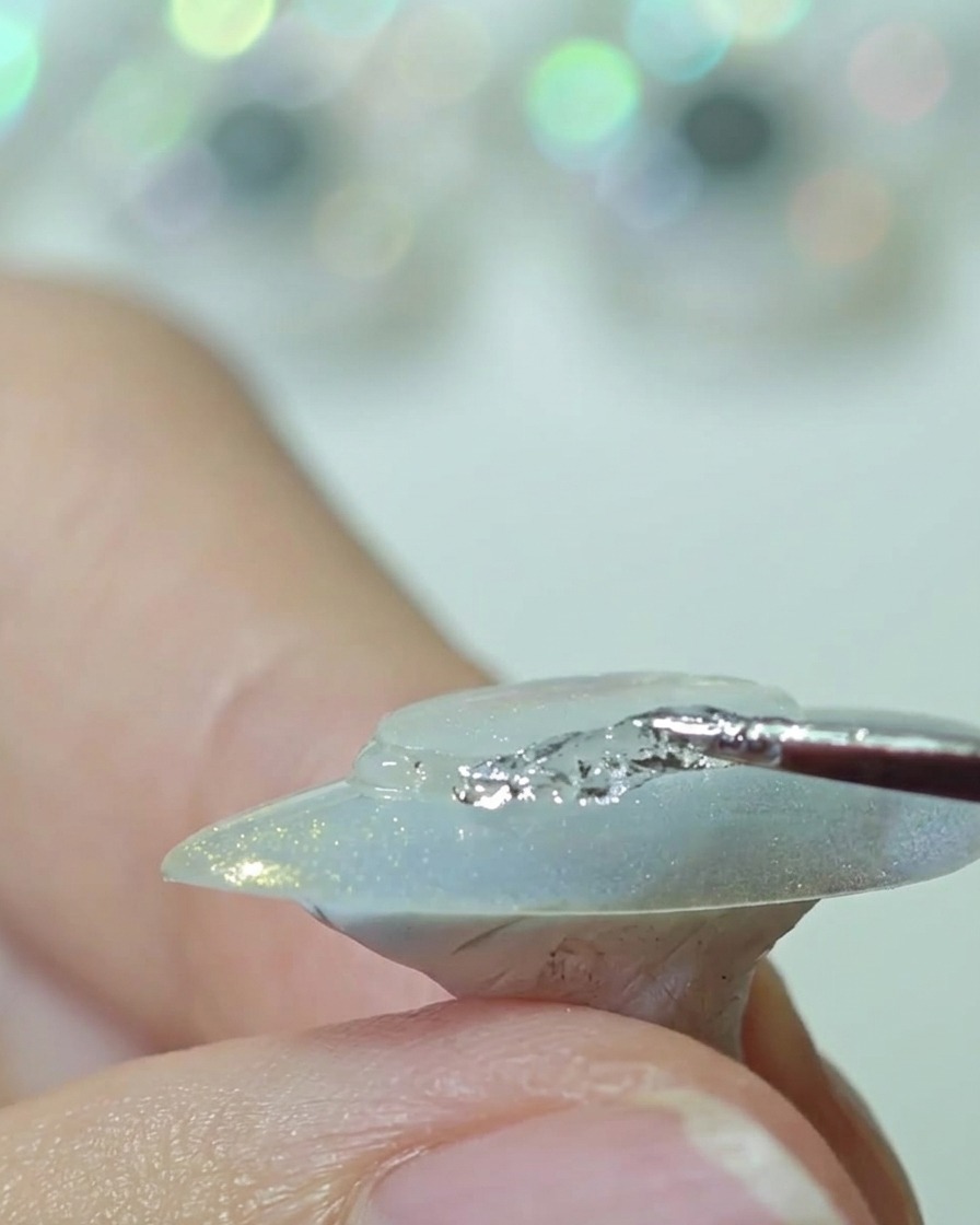 シリコンツールを使って爪中央の透明プラスチックディスクを押し付け、縁を整えている様子。
