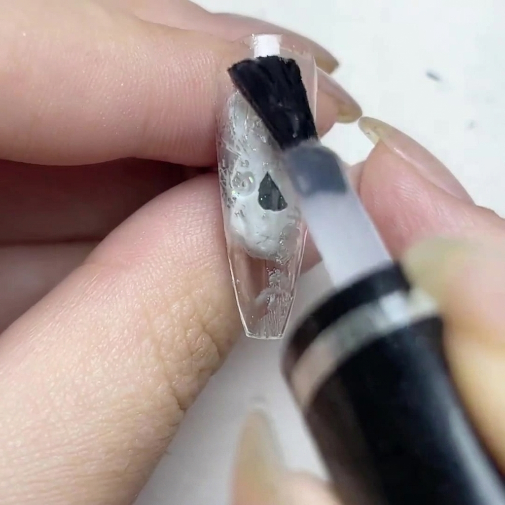 シルバーホイルを貼ったネイルに、マットトップコートを塗っている様子。