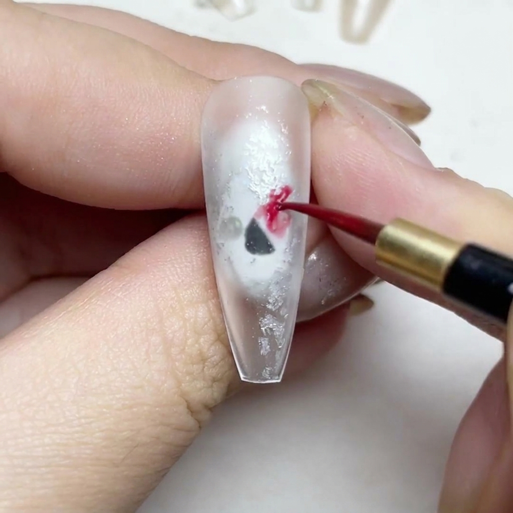 細いライナー筆で、赤い水彩絵具を使って花びらを描いている様子。