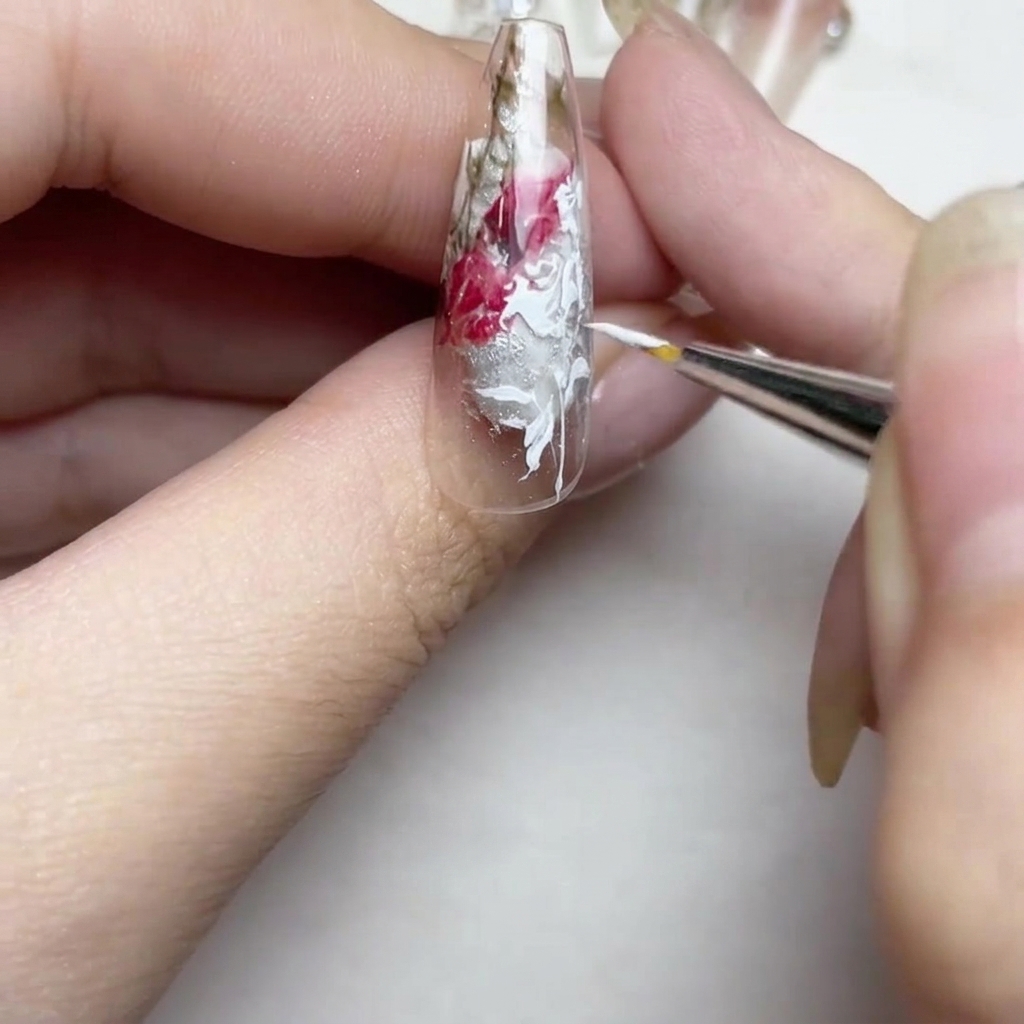 爪先に小さな白い花つぼみを描き、ラインを整えている様子。