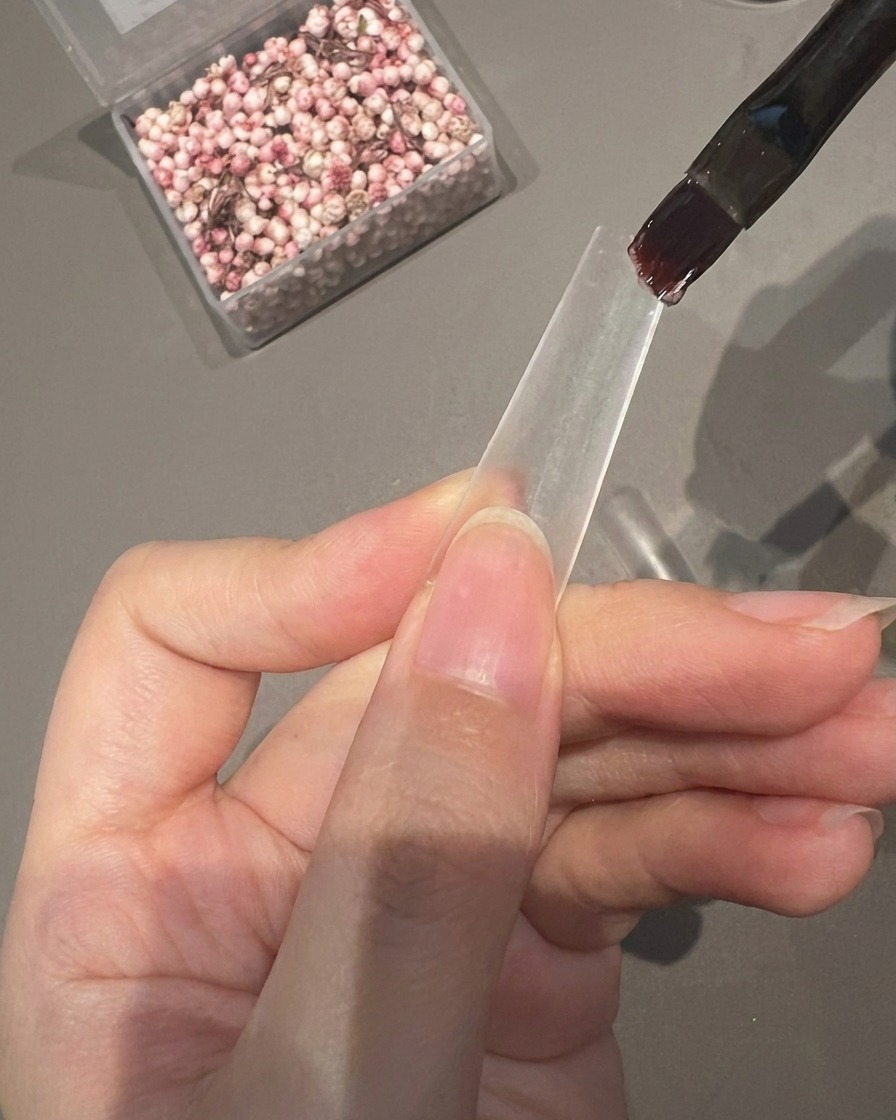 クリアネイルチップの半分にクリア粘着ジェルを塗布している様子。