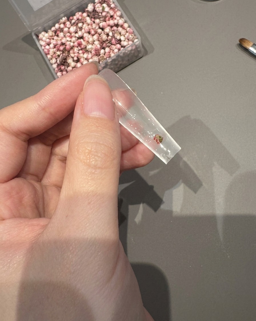 ピンセットでクリアチップの上の粘着ジェルに押し花を置いている様子。