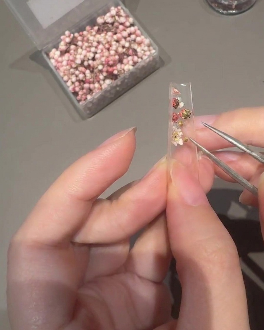 デコレーションされたチップの上にクリアのビルダージェルを塗っている様子。