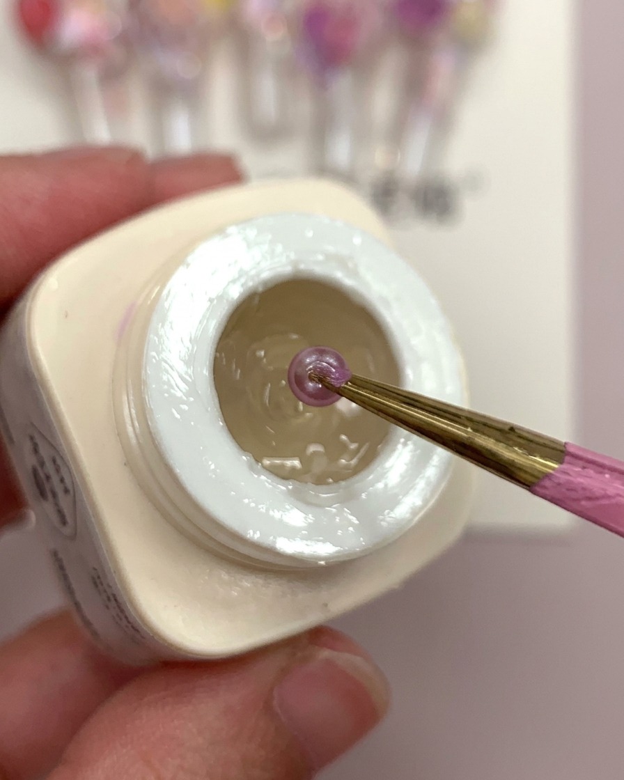 ジェルを乗せた爪に、ピンセットでフラワーボールを配置している様子。