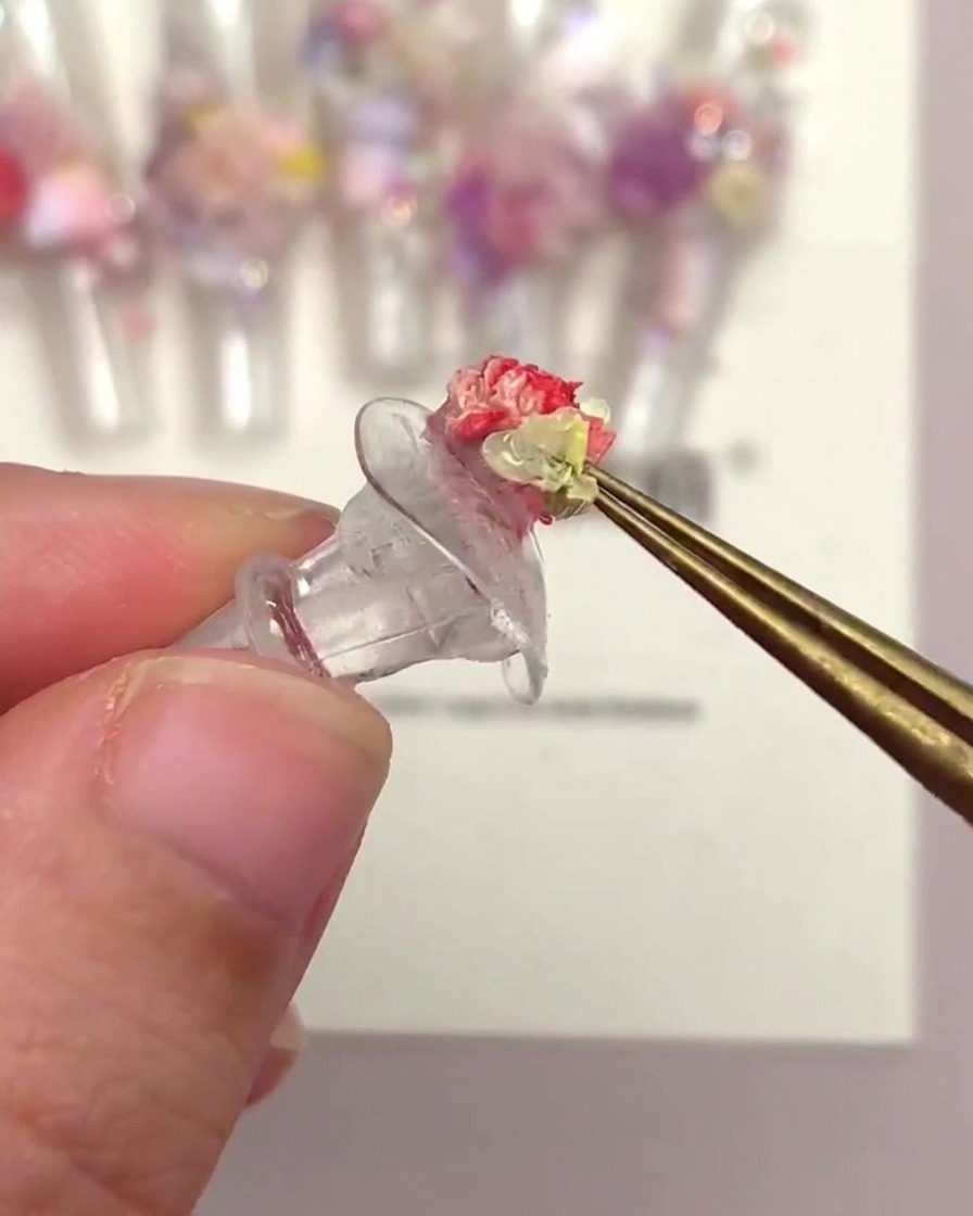 ピンセットでトランペット型花材を爪に配置している様子。