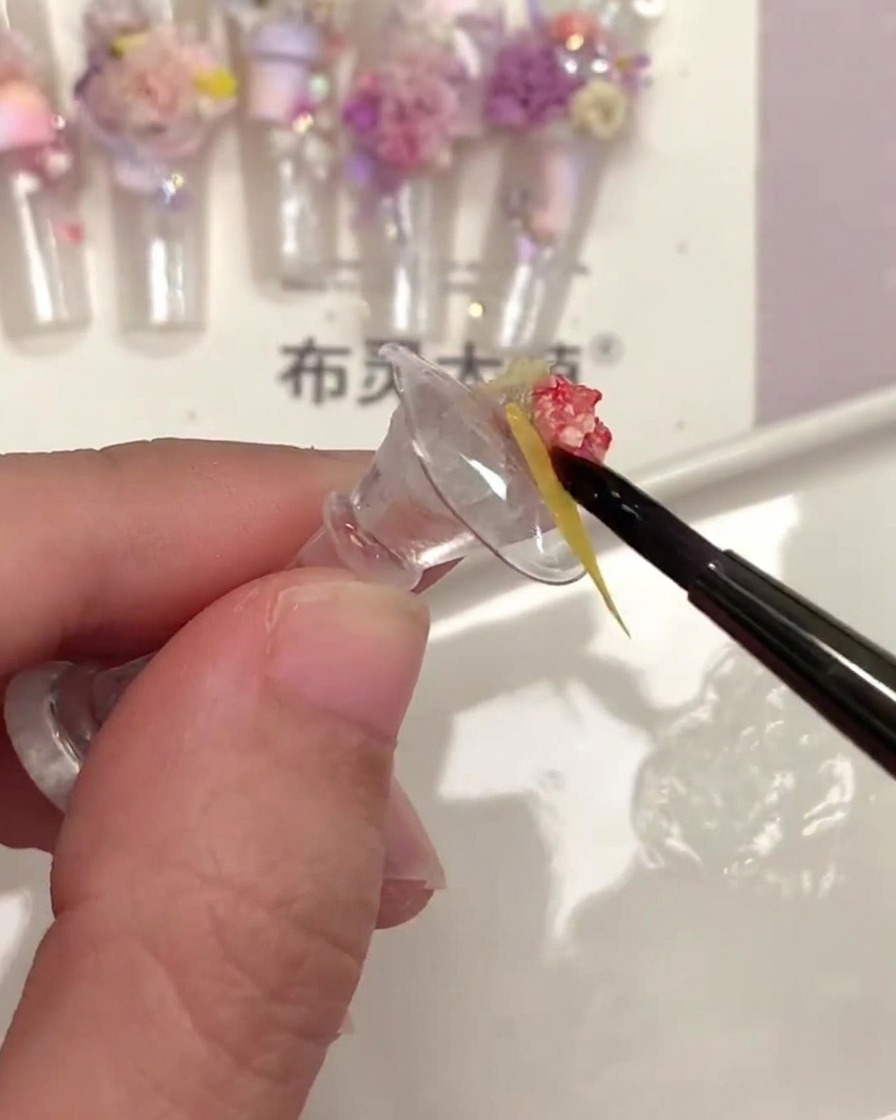 細い筆で花の隙間にトップコートを塗り込んでいる様子。