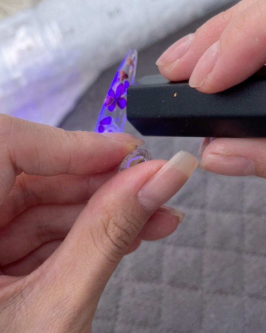 UV/LEDランプの下で花とストーンを埋め込んだチップを硬化させている様子