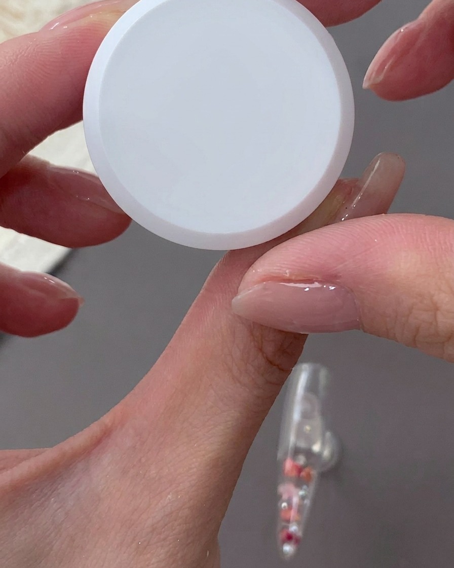 スポンジを使ってネイルの根本側に乳白色のジェルを叩き込んでいる様子