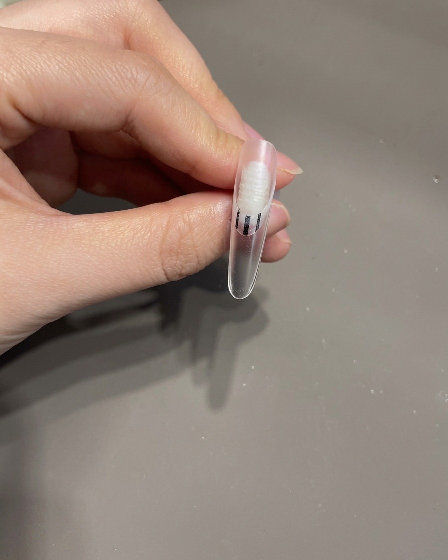 ピンセットで3Dリボンを掴み、爪の上に載せている様子。