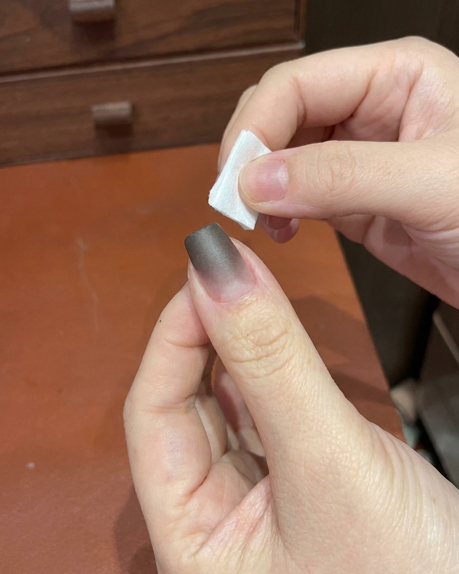 小型の携帯用UV/LEDネイルライトの下に指を置いている様子。