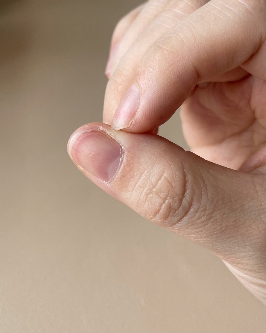 マニキュアが完成した爪の周りの皮膚にキューティクルオイルペンを塗布しているクローズアップ。