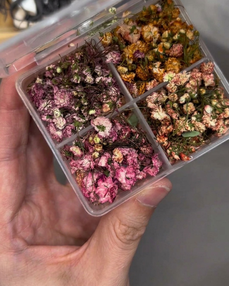 ピンセットで押し花をネイルチップ上のベース層に配置している様子