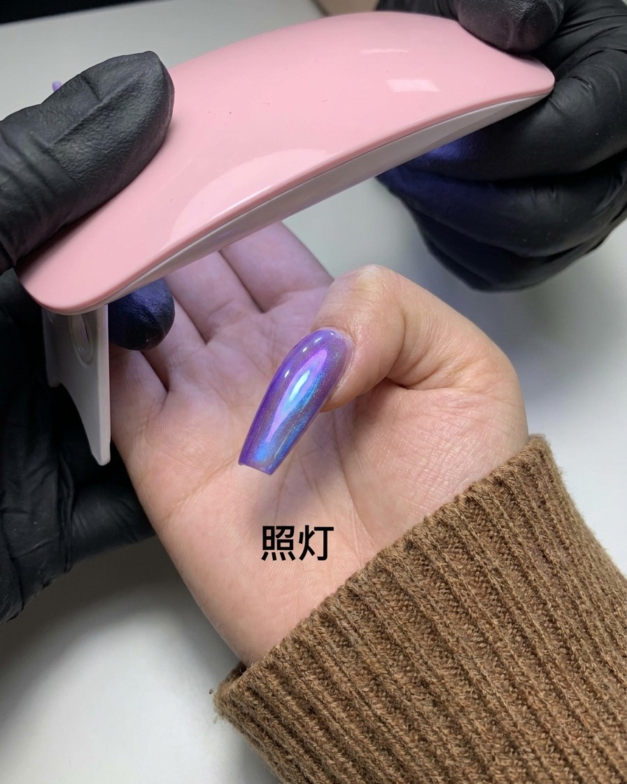 マグネットの模様が完成した指を、小さなピンク色のUV/LEDネイルライトの下に入れている画像。