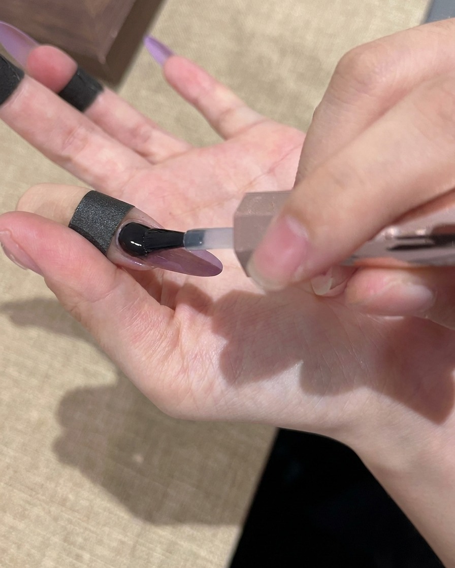 クリアジェルでネイル全体を覆い、艶出しを行う様子