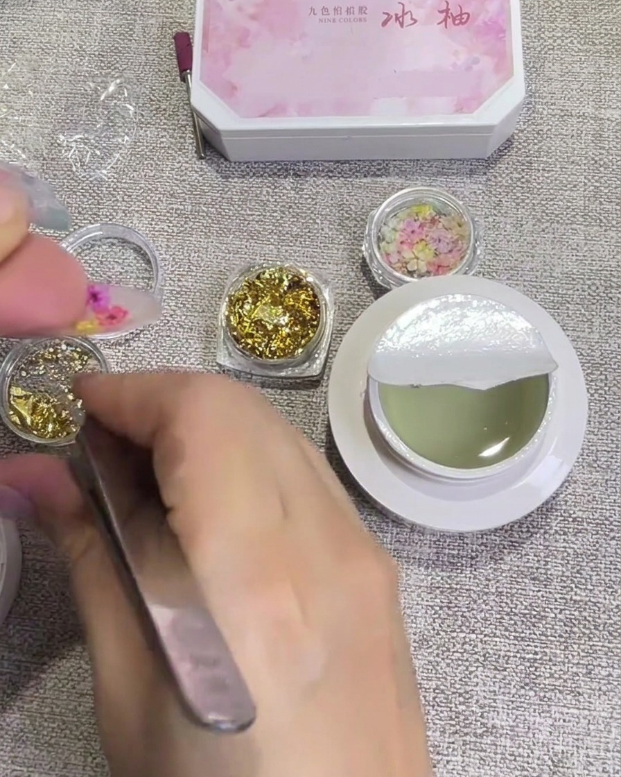 ピンセットを使って、押し花の間を埋めるように小さな金箔の破片を乗せている様子。