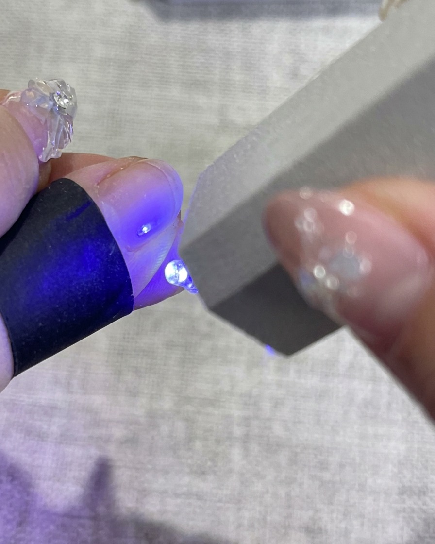 UV/LEDランプの中に手を入れ、ブルーの光を浴びている様子。