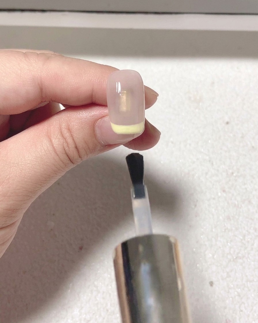 レッドのフレンチネイルの上にマットトップコートを重ね塗りしている様子。