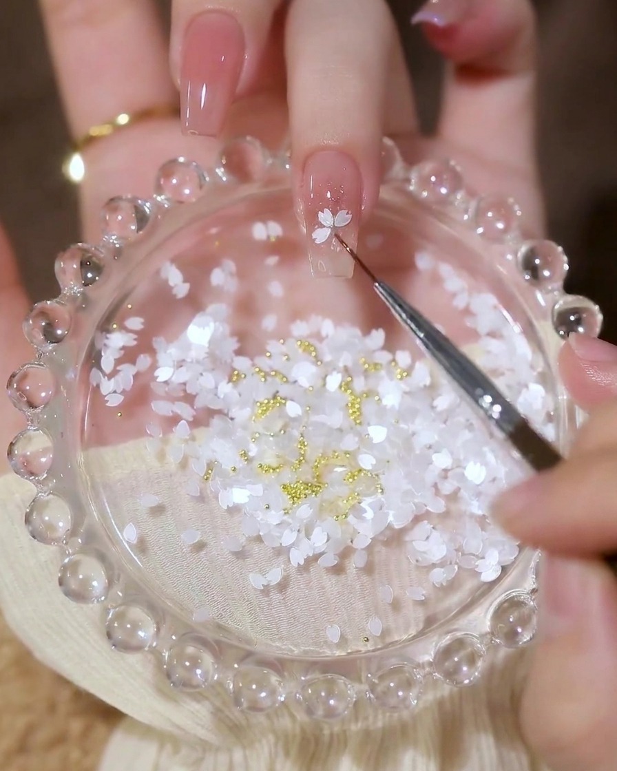 アート筆の先端を使って、白い花びら型のホログラムを爪の上に並べて花の形を作っている様子。