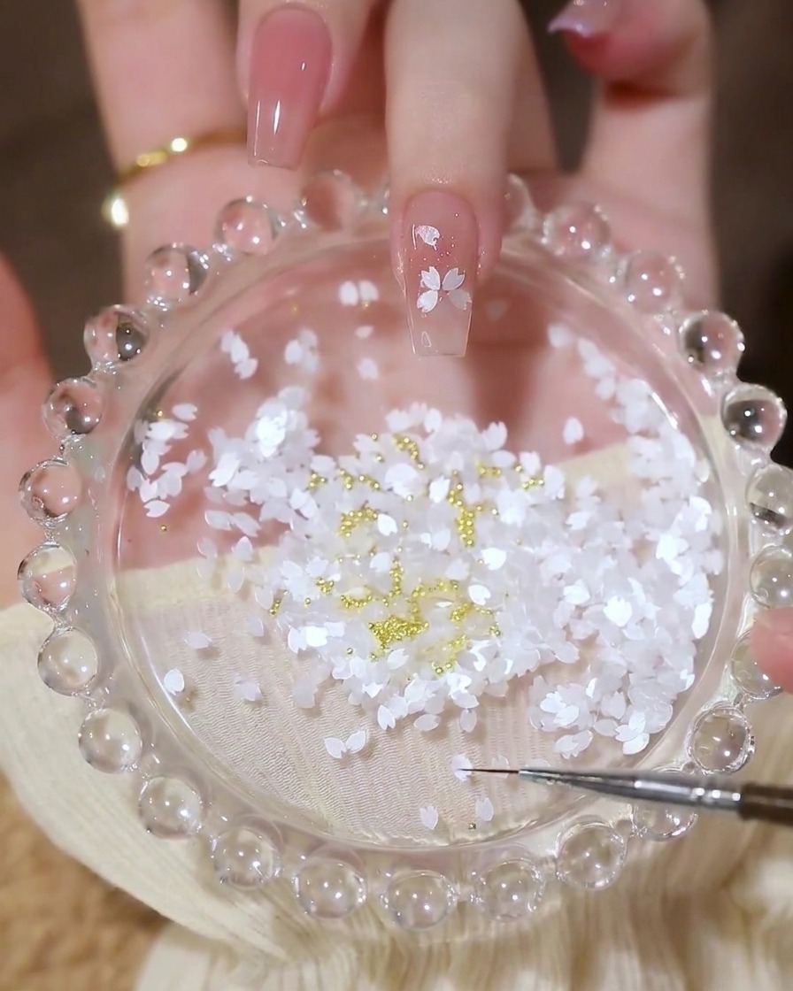 花びらのホログラムで作った花の形の中央に、小さなゴールドのブリオンを配置している完成間近のネイル。