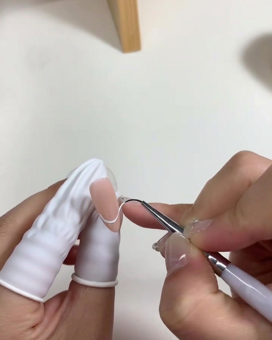 爪の根元側にミルキーホワイトのジェルを薄く塗布しているブラシ。