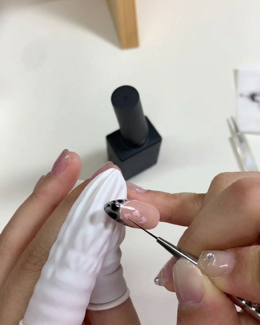 手をポータブルのミニUV/LEDライトの下に置き、ピンクの桜のアートを硬化させている様子。