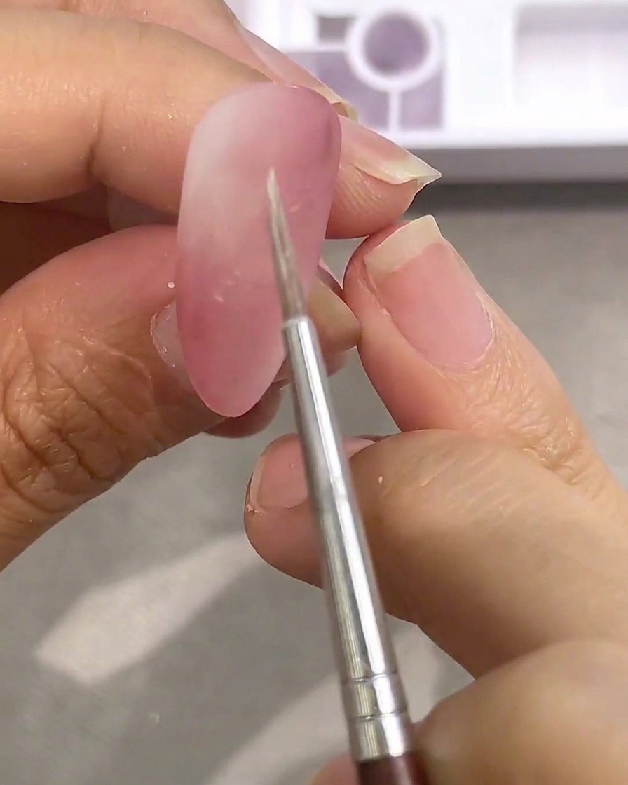 パレット上の白い水彩絵の具に細筆を浸しているアップ画像