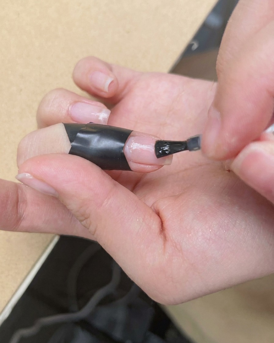 ブルーミングジェルが塗られた爪の中央に、細筆で鮮やかなピンク色のドットを置いている様子。