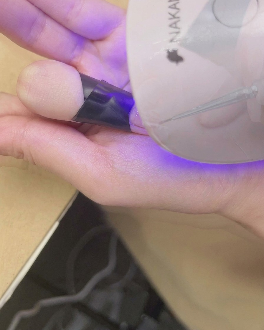 仕上がったチークネイルを小型UV/LEDライトに入れて硬化させている様子。