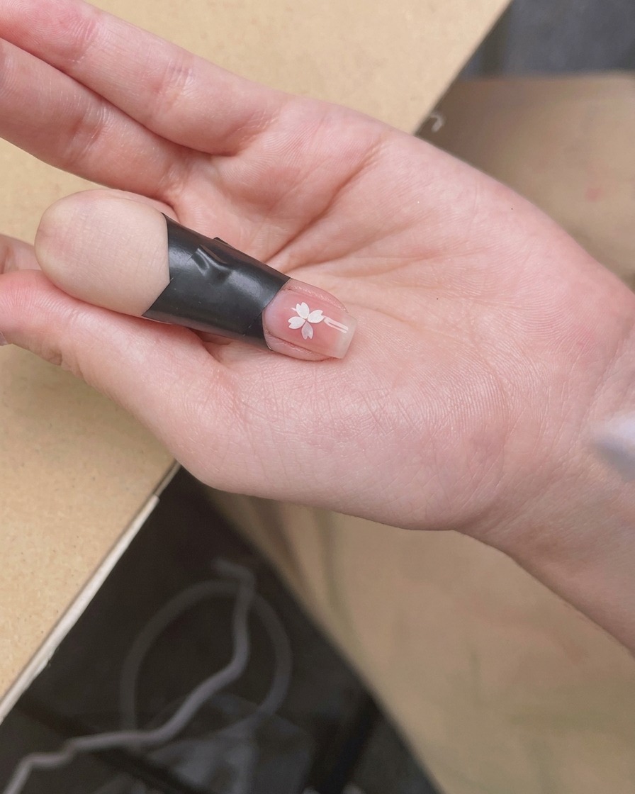 パーツを乗せた爪を小型UV/LEDライトに入れ、しっかりと硬化させている様子。