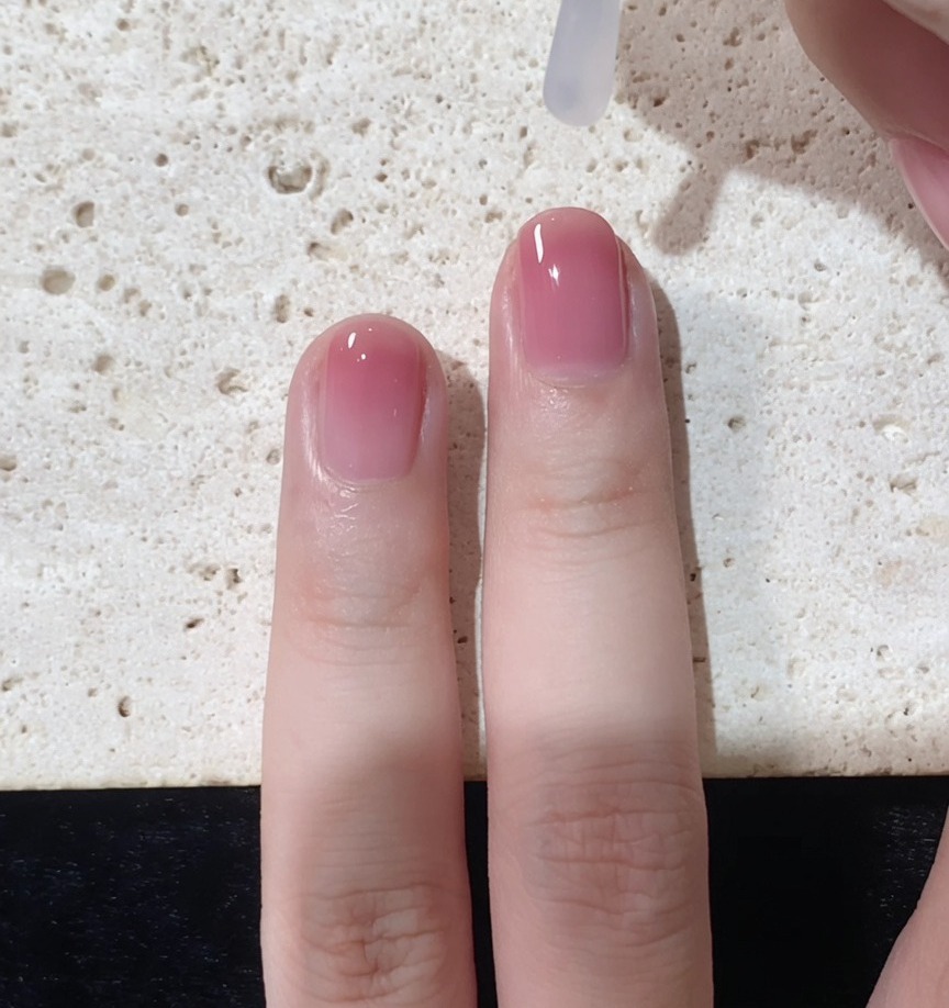 完成したグラデーションネイルにクリアのトップジェルを塗っている様子