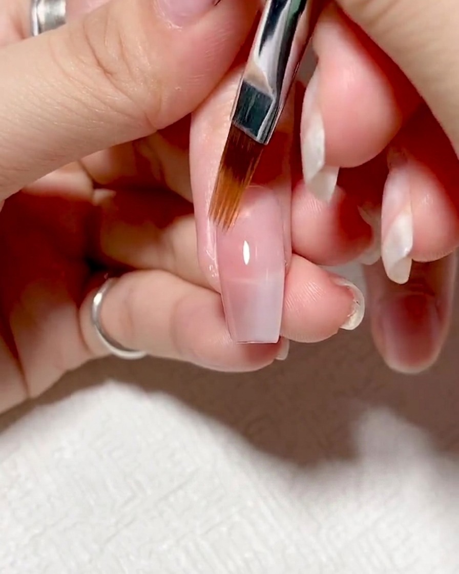 UV/LEDライトの中で、紫色の光を浴びながら硬化しているネイル。