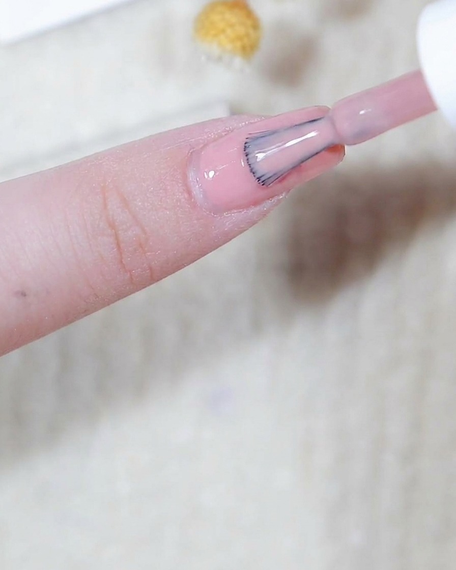 爪全体に薄く均一なピンクのベースカラーを塗布している様子。