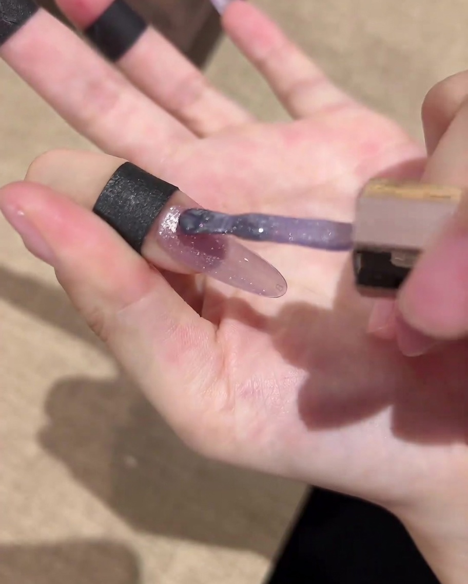 完成したネイルデザインにクリアトップジェルを塗布している様子。