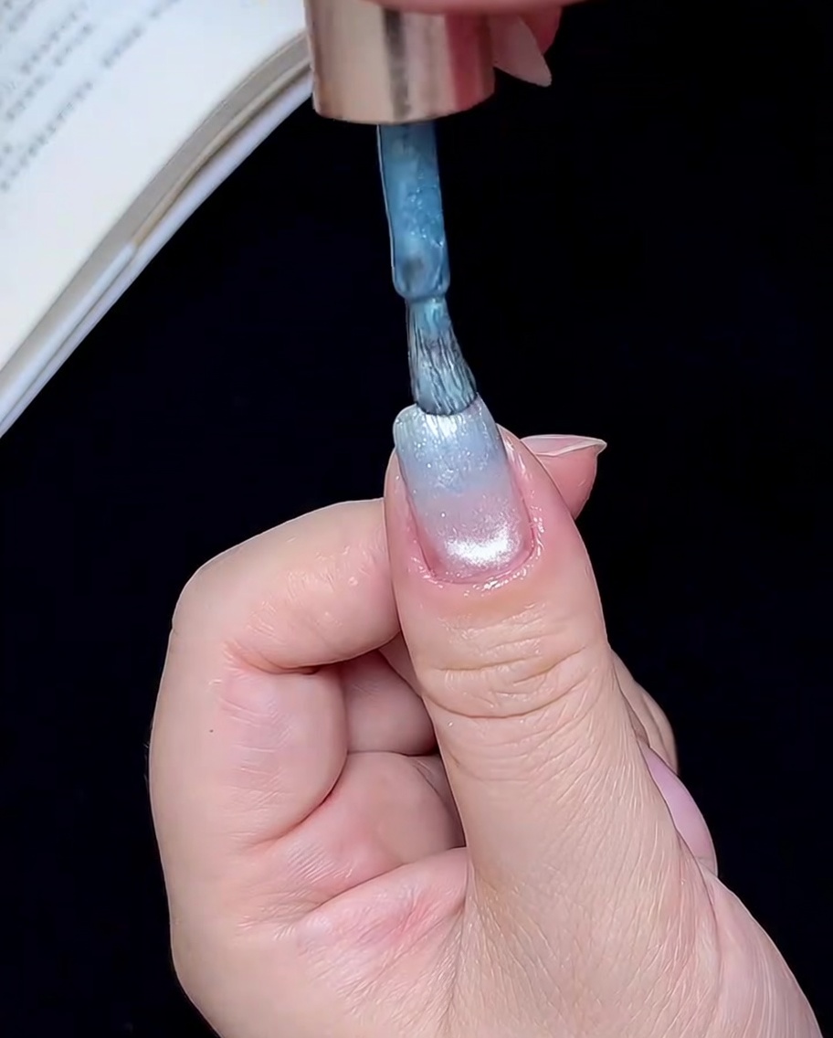 爪先に少量のブルーのジェルをブラシで塗布している様子。